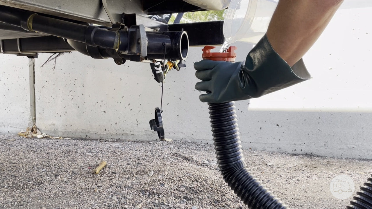 RVer with gloves on, pouring 0.5 gallons of water into the end of an RV sewer hose to prep the sewer hose p-trap so that it blocks odors and sewer gasses