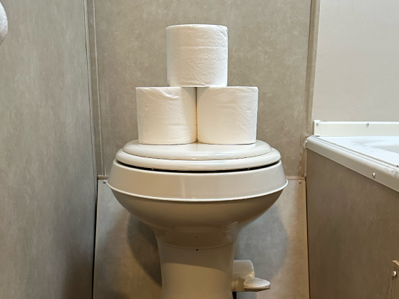 RV bathroom with toilet paper stacked neatly on the toilet. Unique Camping + Marine