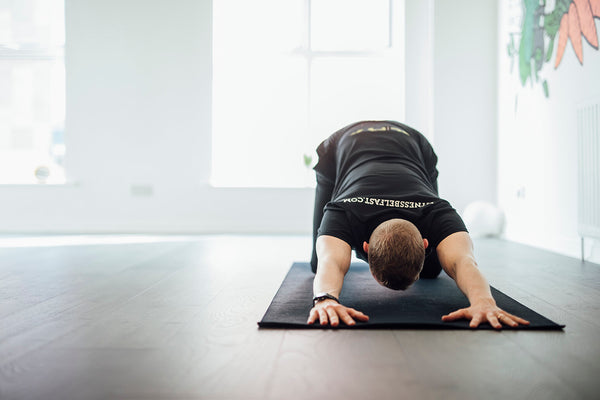 A man performing a yoga stretch in a fitness studio in Belfast.