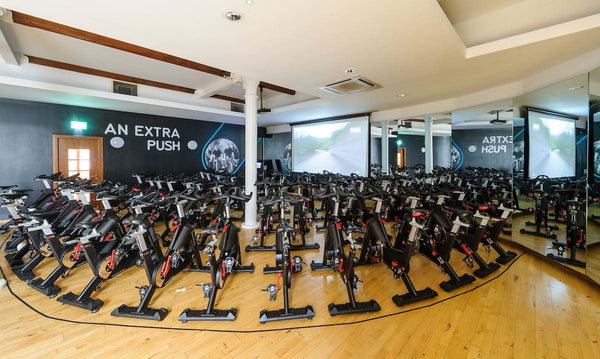 Multiple rows of spinning bikes in a fitness studio.