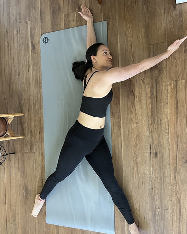 Daniela Spear doing a Davinci Stretch laying on a yoga mat on the floor