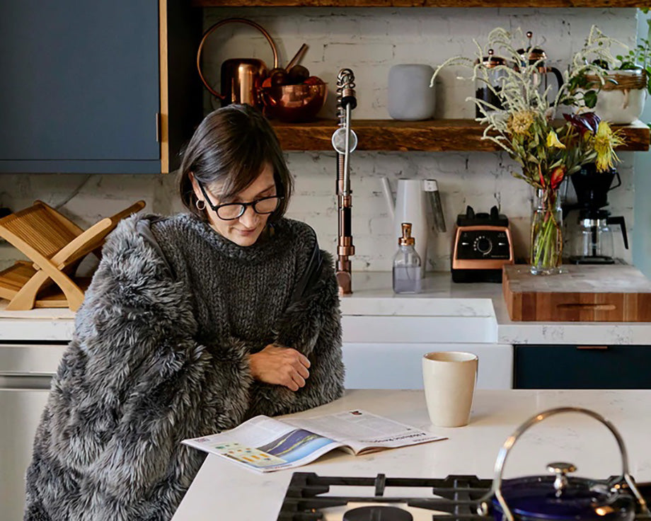a woman reading a magazine while wrapped in a weighted blanket