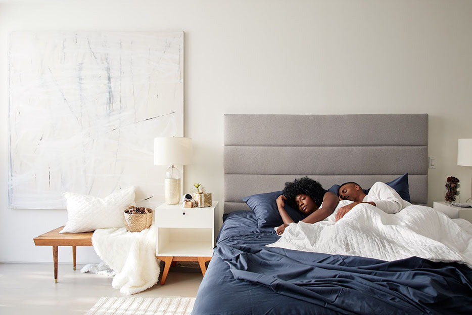 couple sleeping under blanket in bed