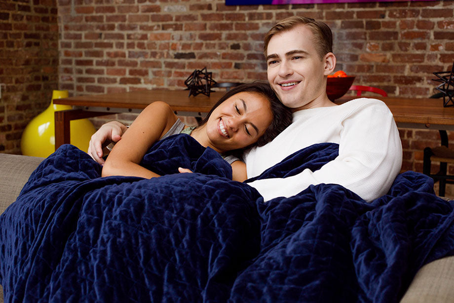 couple snuggle under weighted blanket