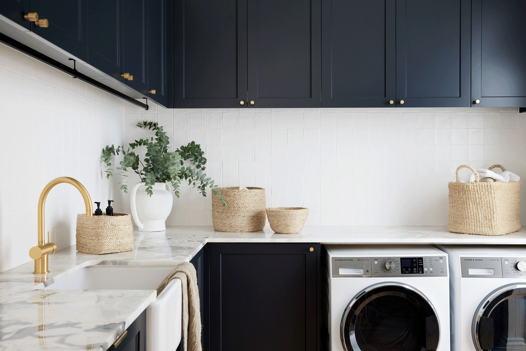 laundry with farmhouse sink, navy blue cabinetry and woven jute baskets