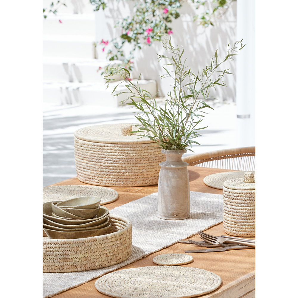 outdoor alfresco summer table setting with palm fibre placemats and green foliage in vase