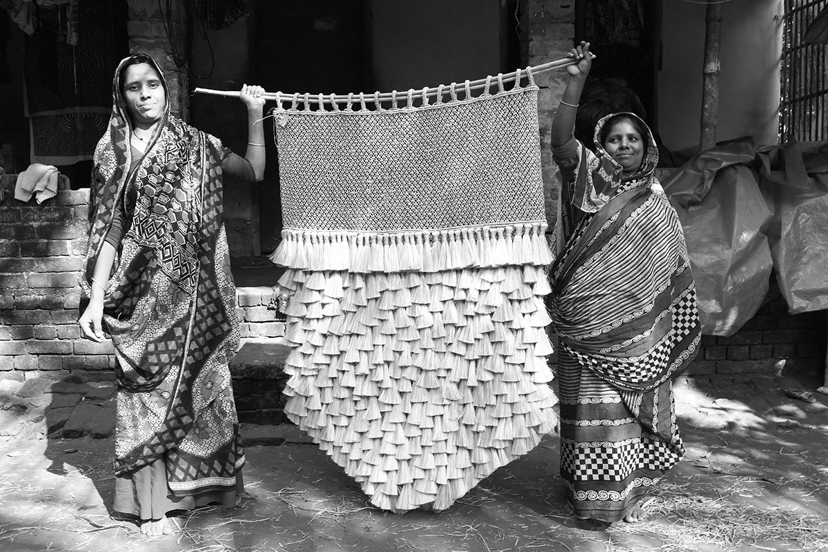 Two proud artisans showing a tassel wall hanging they created
