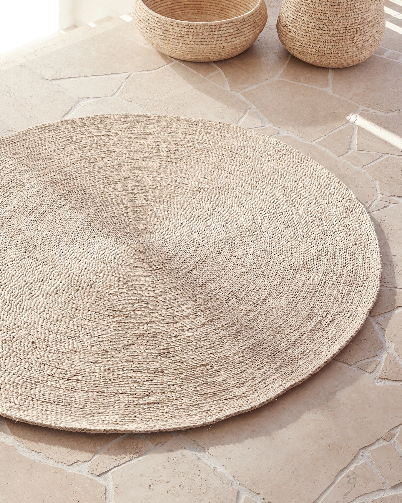 handwoven round jute rug on crazy paving