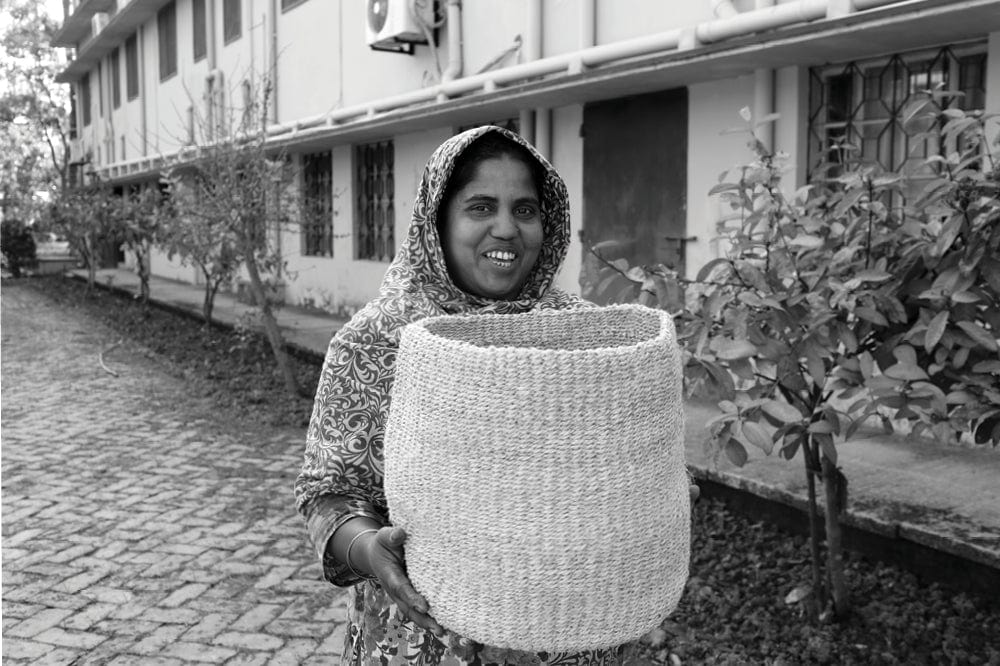 Fair trade artisans - Bangladeshi woman holds basket she made by hand out of natural jute
