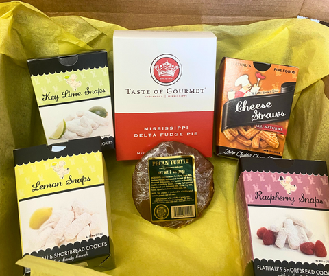 Gift box with yellow tissue paper full of six items: 4oz Key Lime Snaps, 4oz Lemon Snaps, 4oz Raspberry Snaps, 3.5oz Cheese Straws, 2oz Pecan Turtle, Taste of Gourmet's Delta Fudge Pie Mix