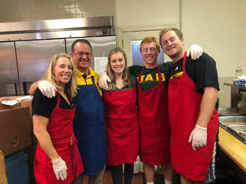 Family of five standing in a kitchen wearing matching red aprons; From left to right: Heather Flathau, Jeff Flathau, Hannah Flathau, Heath Flathau, and Tyler Flathau