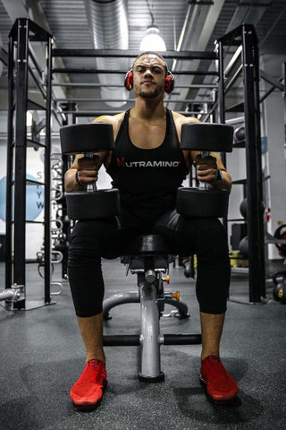 Man lifting weights seated wearing headphones