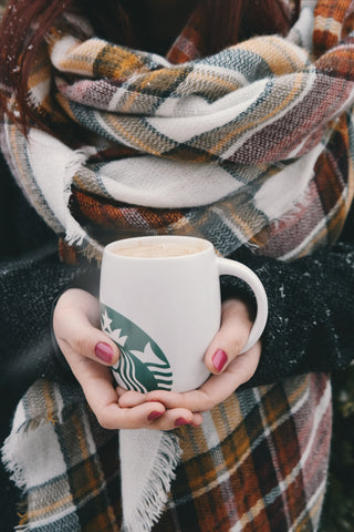 Frau trägt dicken Schal und hält Kaffeetasse in der Hand