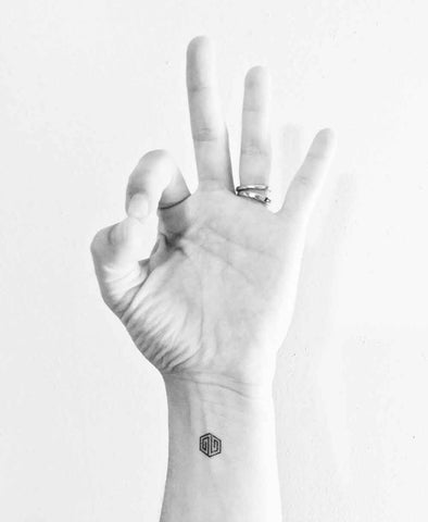 Teacher Natasha Akery's hand in mudra and with a temporary tattoo on her wrist that means - I allow life to nourish me.