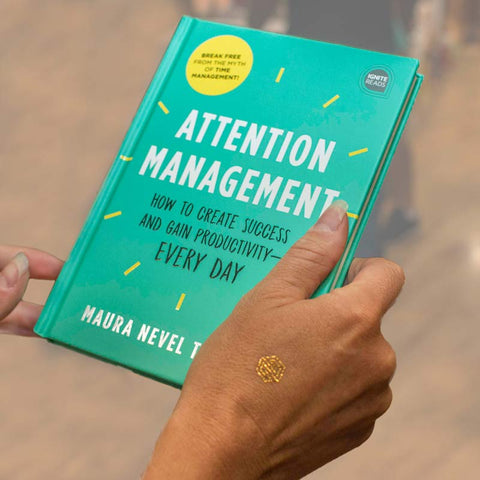 Attention Management Book held by woman wearing gold mindfulness temporary tattoo.
