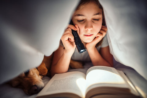 Girl Reading Book under blanket