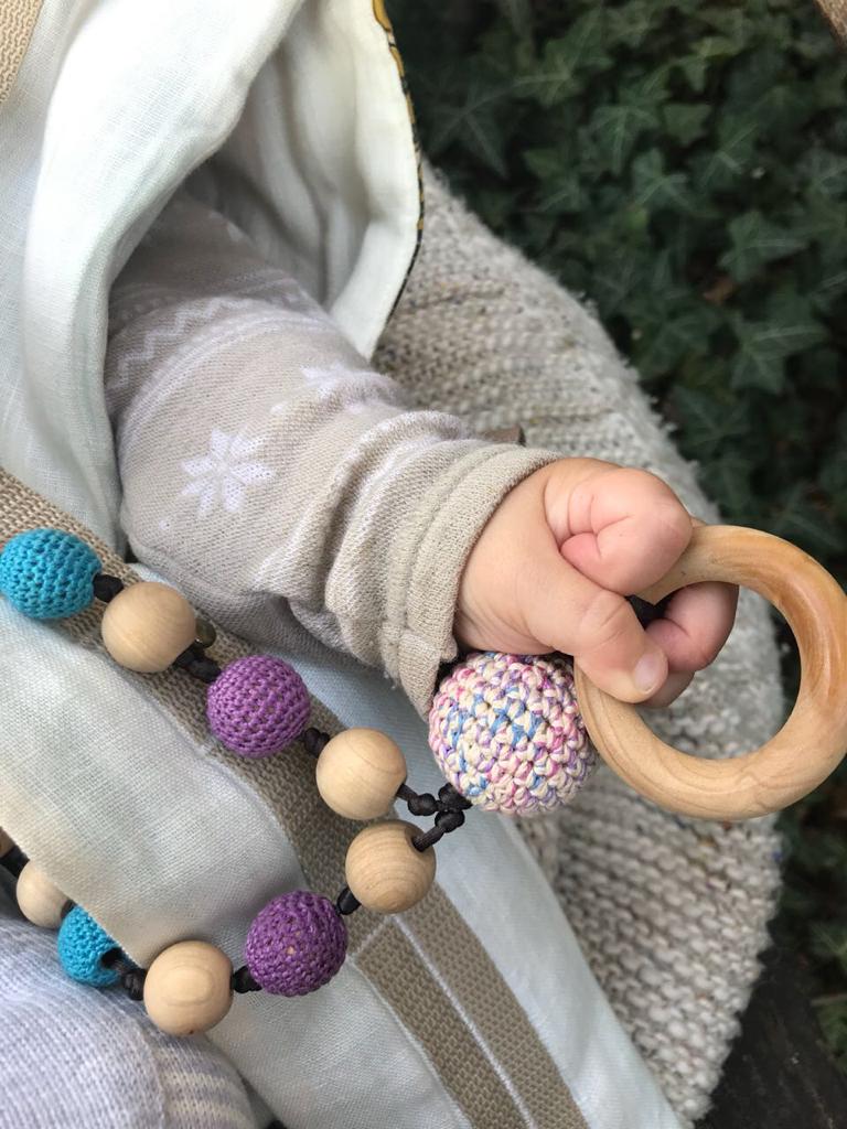 A teething baby playing with the olive wood nursing necklace by little olea | Handmade Palestine