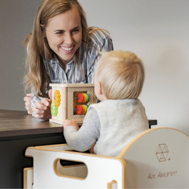 Lady using the arc assistant learning tower with her toddler in the kitchen