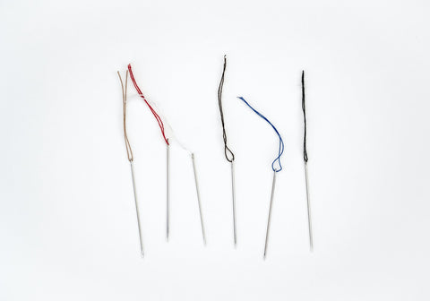 Six sewing needles with various colors of thread