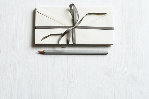 Envelopes tied together with ribbon and grey pencil