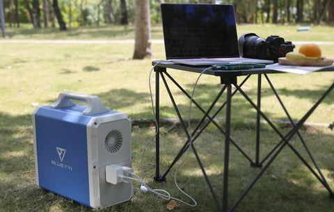 Photo of Bluetti - EB240 2400Wh/1000W Portable Power Station hooked in a laptop on the ground.