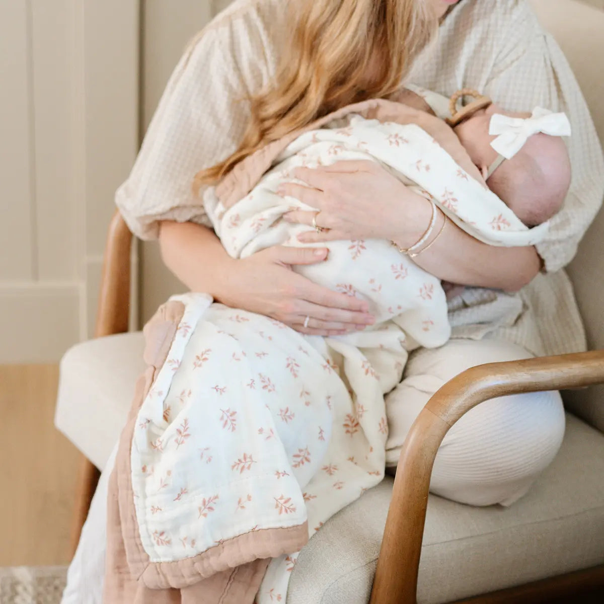 A woman gently cradles her newborn while seated in a cozy chair, radiating warmth and tenderness.