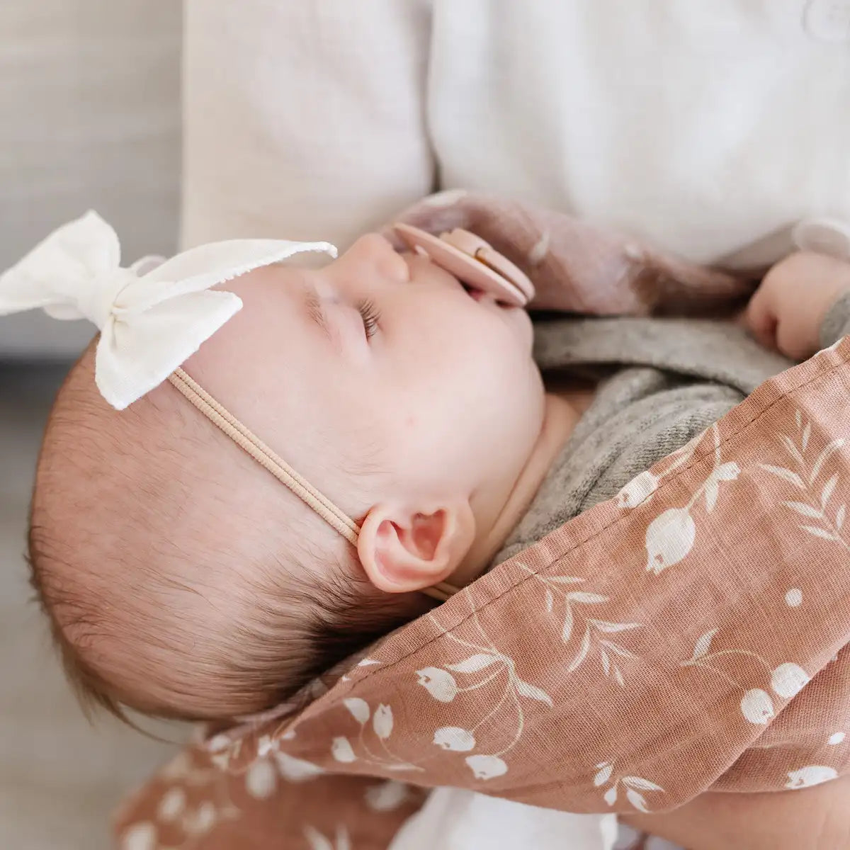 A woman cradles a baby wrapped in a pink floral fabric, showcasing a tender moment of care and connection.