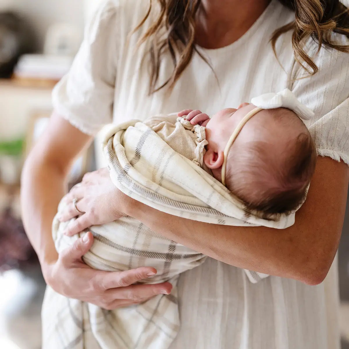 A woman gently holds a baby wrapped in a soft blanket, showcasing a tender moment of care and affection.