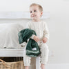 An adorable baby boy holds his faux fur forest green baby blanket.