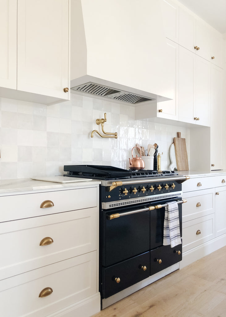 Neutral kitchen with black stove and gold hardware