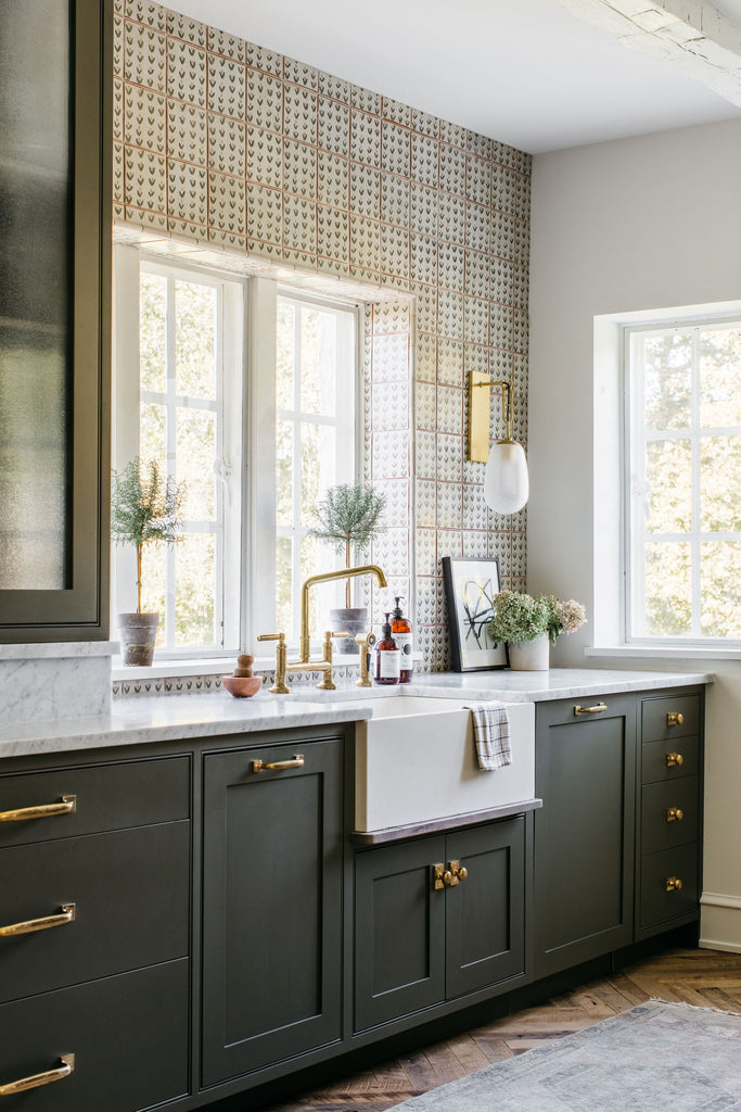 window and kitchen sink, green painted cabinets, brass hardware and tap