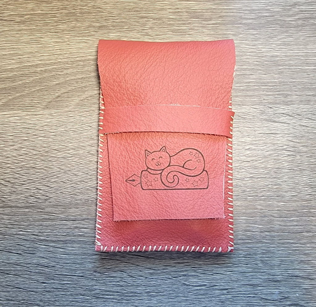 Leather pen pouch with a cat design engraved on it.