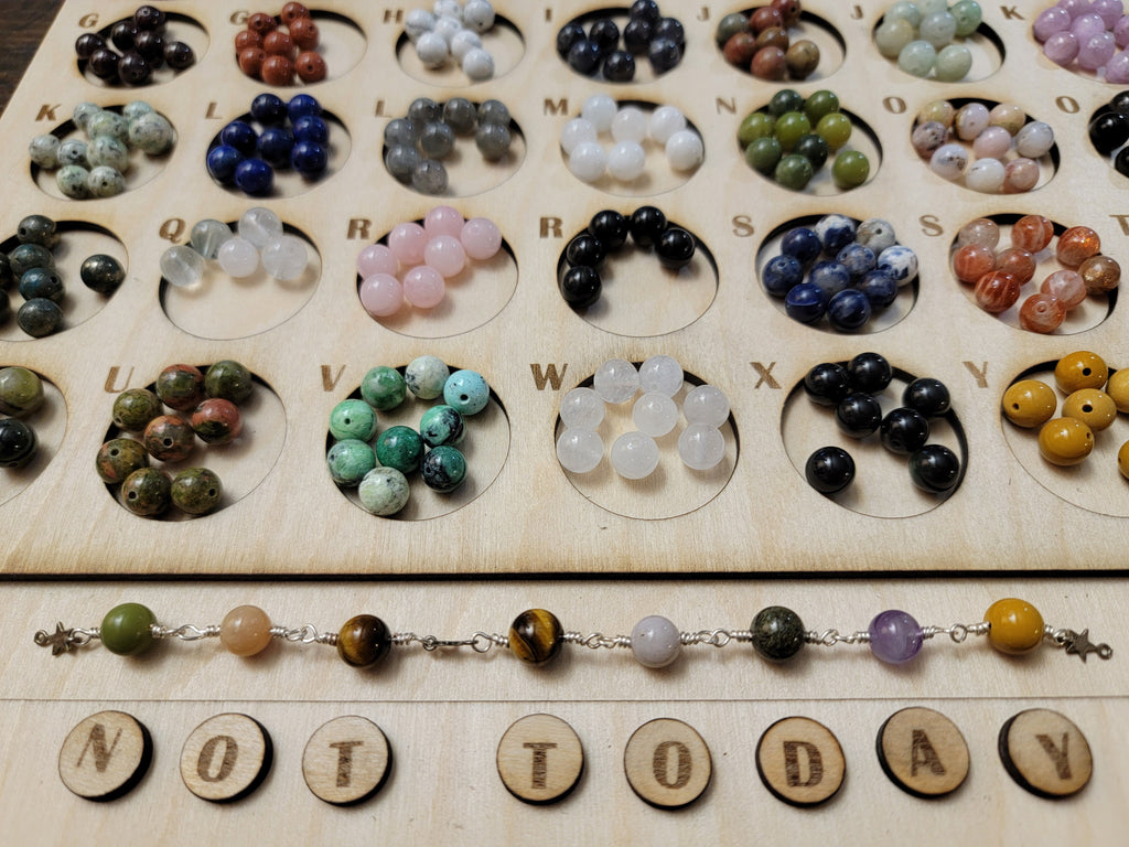 necklace that spells out "not today" on the bead tray