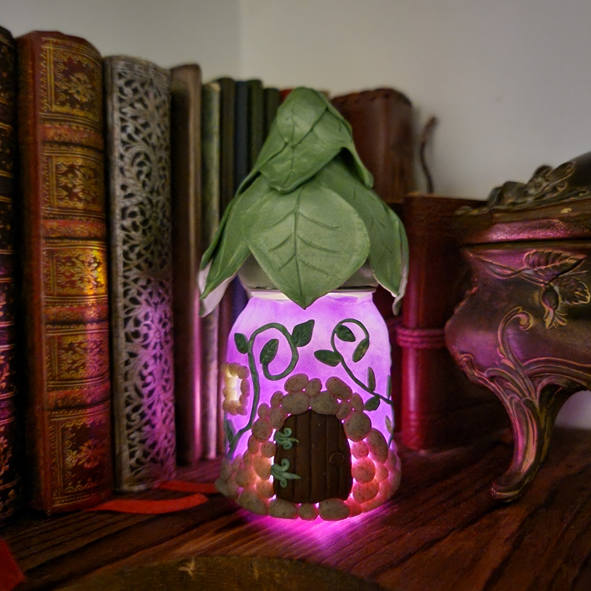 a lit up fairy house on a bookshelf