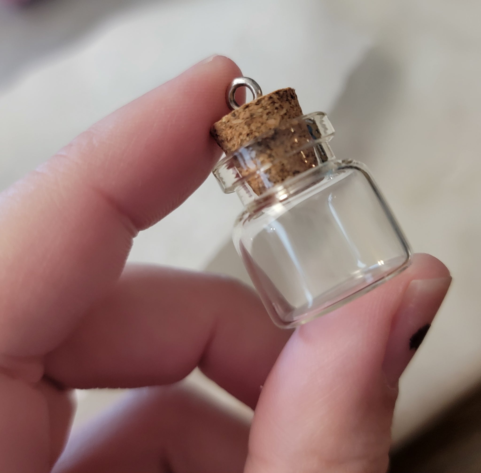 a small glass jar between two fingers