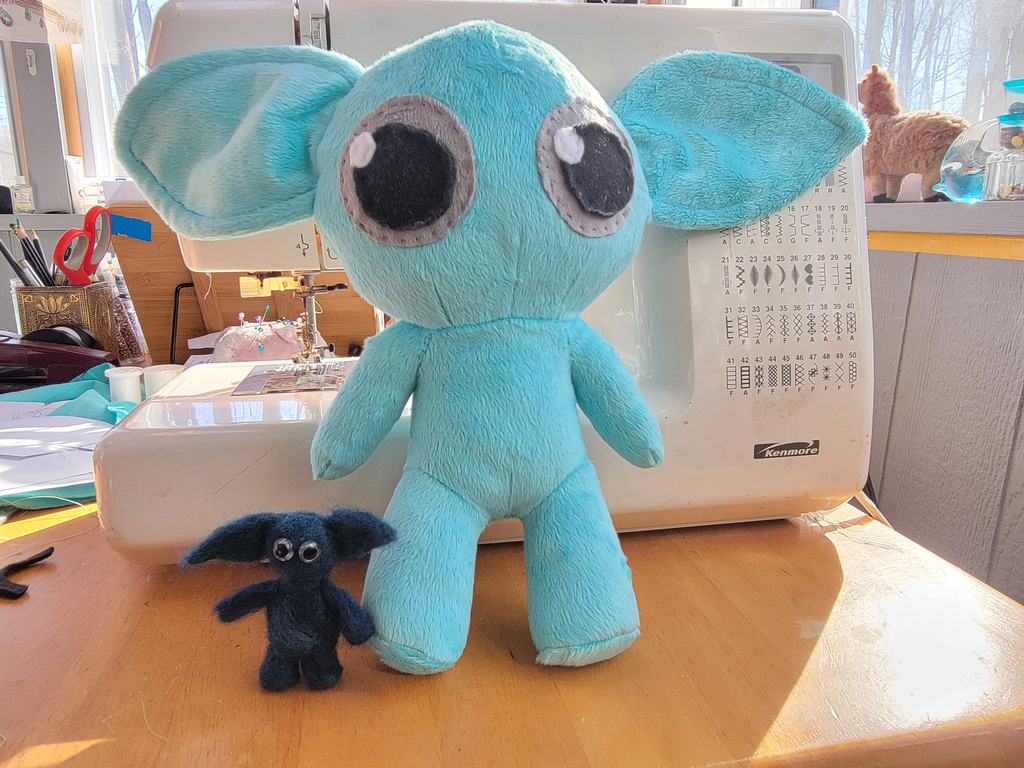 A mini needle felted gremlin next to the first test plush gremlin