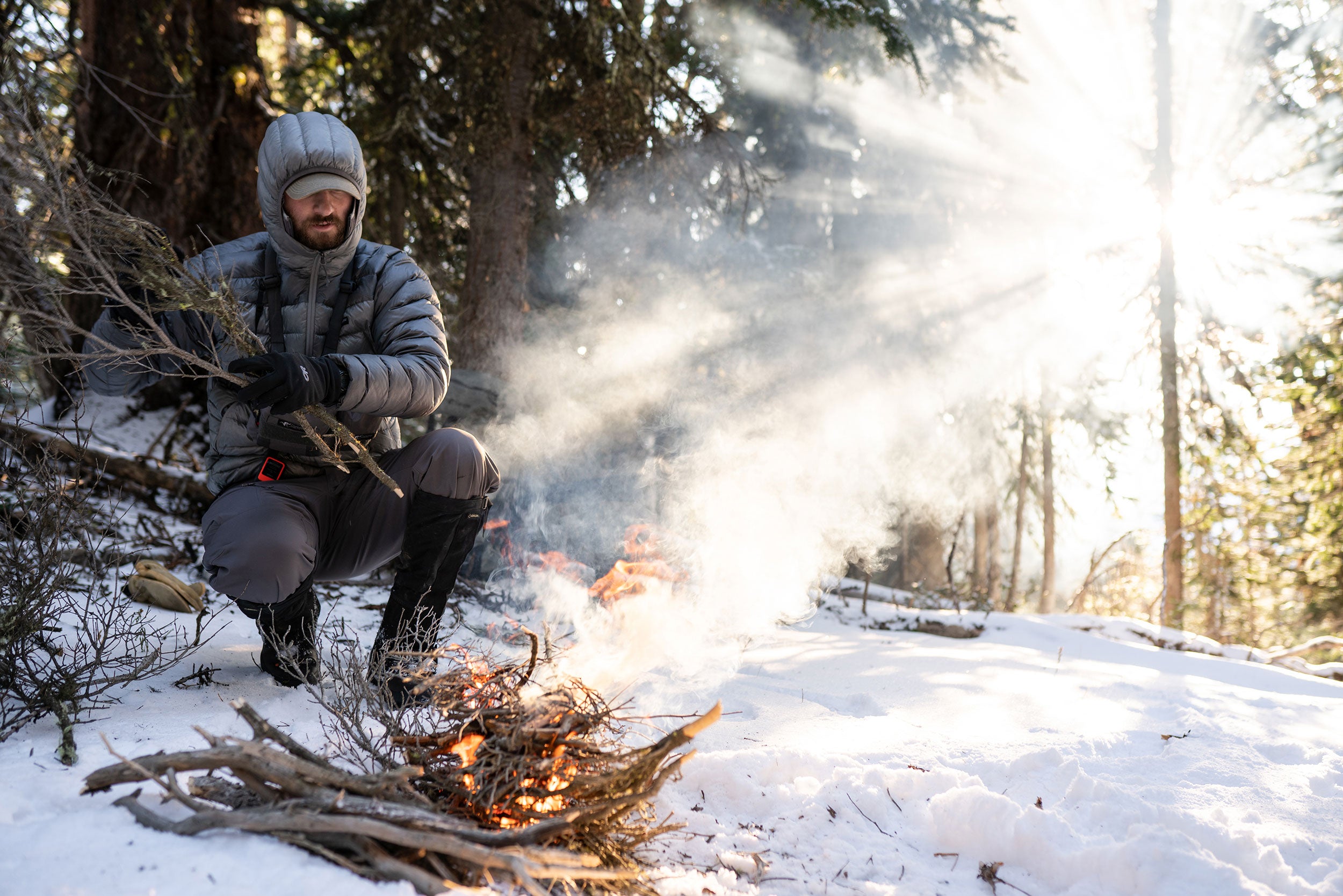 Hunter building a fire in the snow.