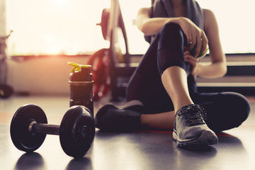 person sitting on ground at the gym with hand weights