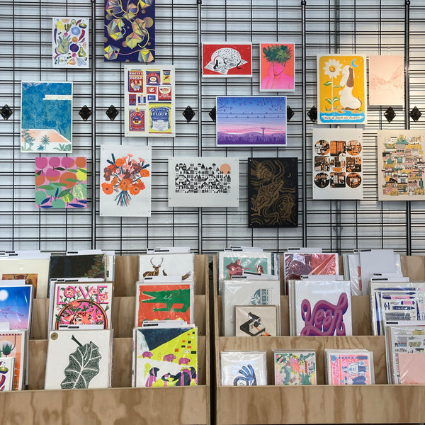 A gallery wall in a shop of bright, colourful prints by different printmakers.