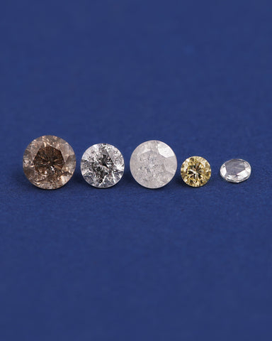 Five round salt and pepper diamonds of various colors lined up on a dark blue background 