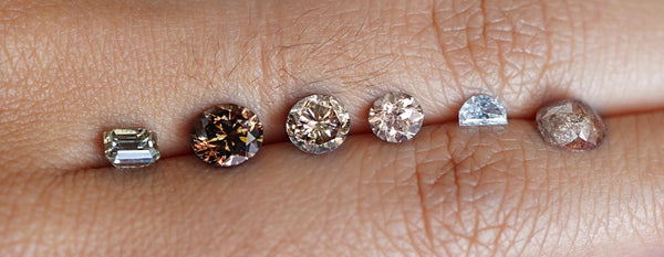 Natural diamonds of various colors resting between two fingers