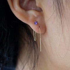 Close up view of a model's ear wearing an amethyst Gemstone Threader through two piercings