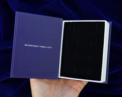 A dark blue and white Automic Gold book box open to show the soft foam inside