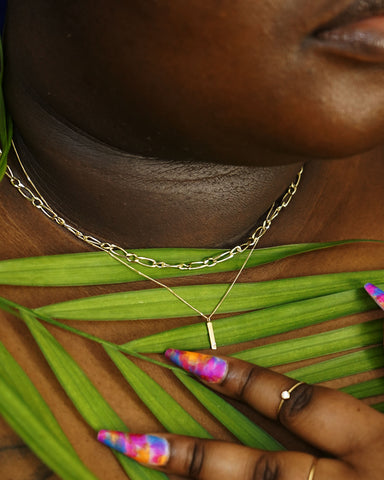 A model holding a leaf to their chest wearing a Butch Chain and a Bar Pendant Necklace