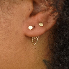 Close up view of a model's ear wearing two Circle Studs with a yellow gold Cable Chain Connector behind their lobe