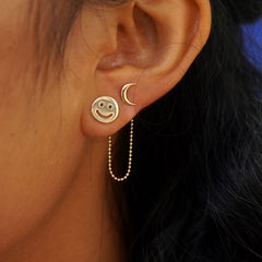 Close up view of a model's ear wearing a Connector between a Smiley Face Earring and a Moon Earring