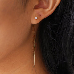 Close up view of a model's ear wearing a yellow gold and diamond Gemstone Threader dangling straight from a single piercing