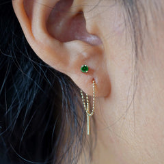 Close up view of a model's ear wearing an emerald Gemstone Threader through two piercings