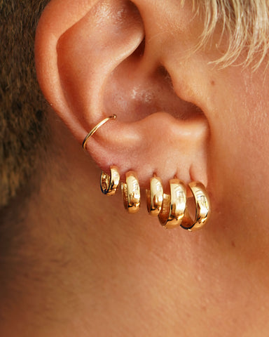 A model wearing multiple sizes of hoop earrings