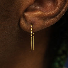 Close up view of a model's ear wearing a solid 14k yellow gold Mini Threader